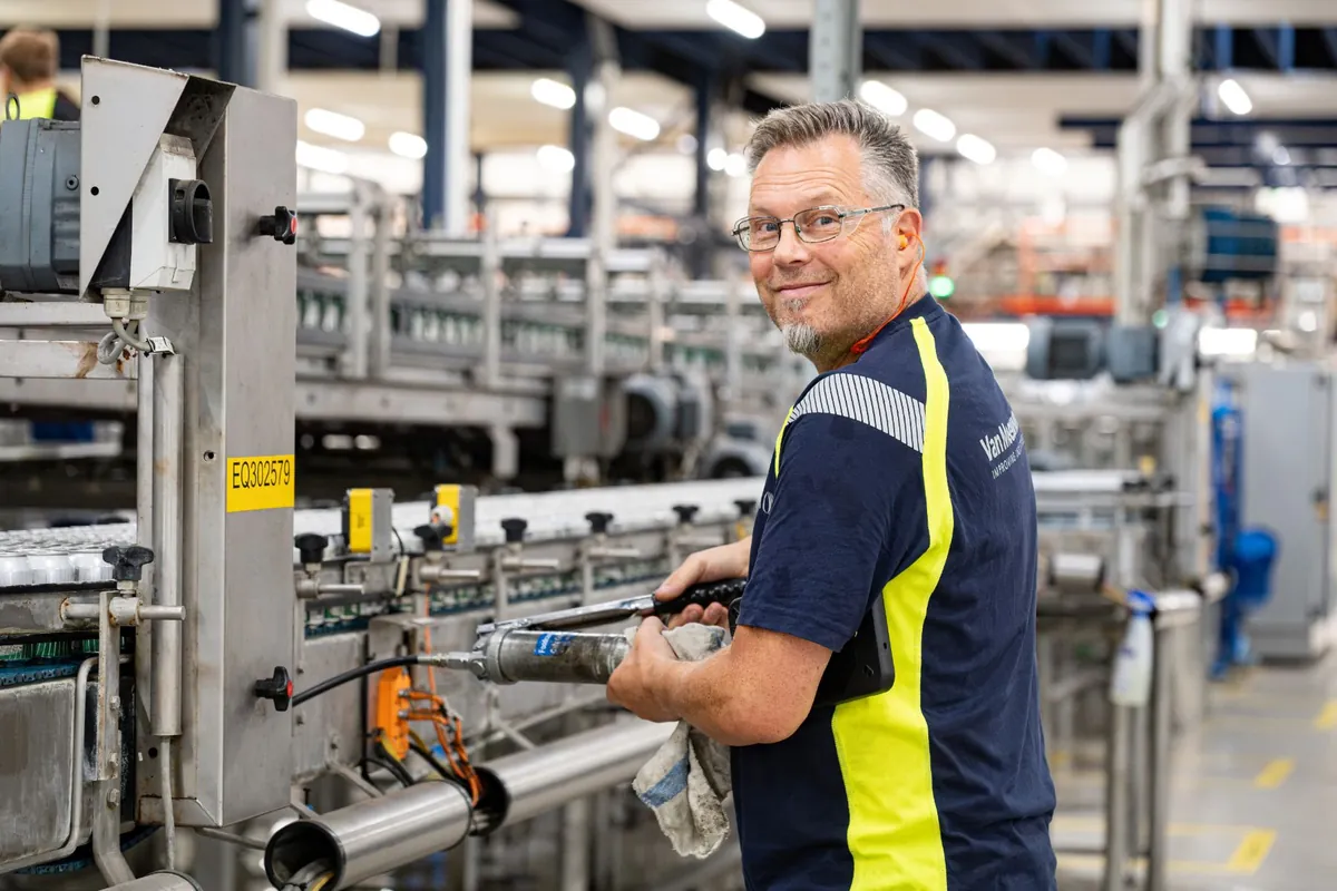 Monteur smeert een transportband, met de tablet onder de arm